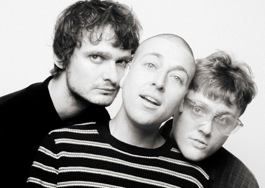 The three members of MOULD with their heads pressed togetherx